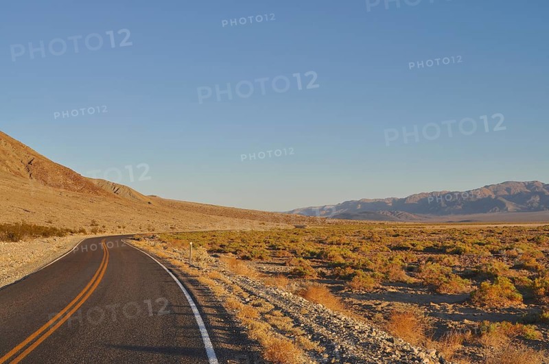 Lonely road through the desert in evening light with mountains in the background, Death Valley National Park, Mojave Desert, California, Nevada, USA