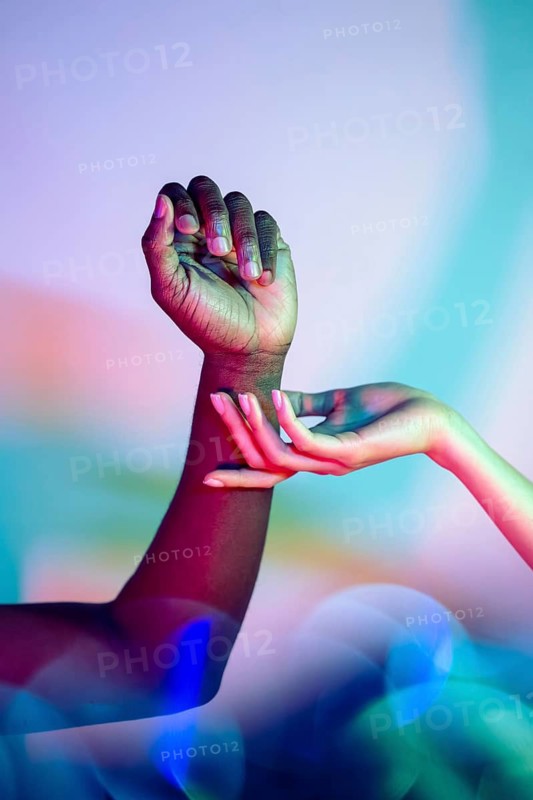 Vibrant image of multiethnic hands against a colorful background, symbolizing unity and diversity. Captures an artistic play of light and shadow, emphasizing cultural harmony