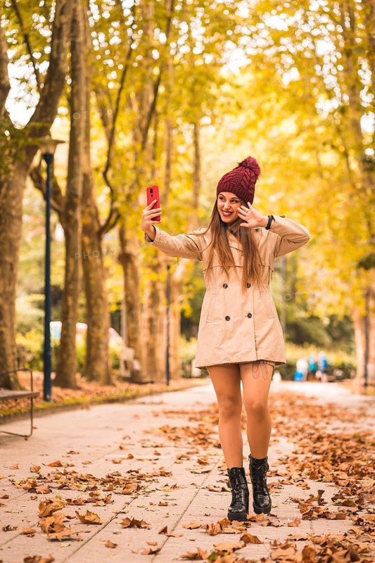 Portrait of a beautiful woman in autumn next to a forest in nature making a video call