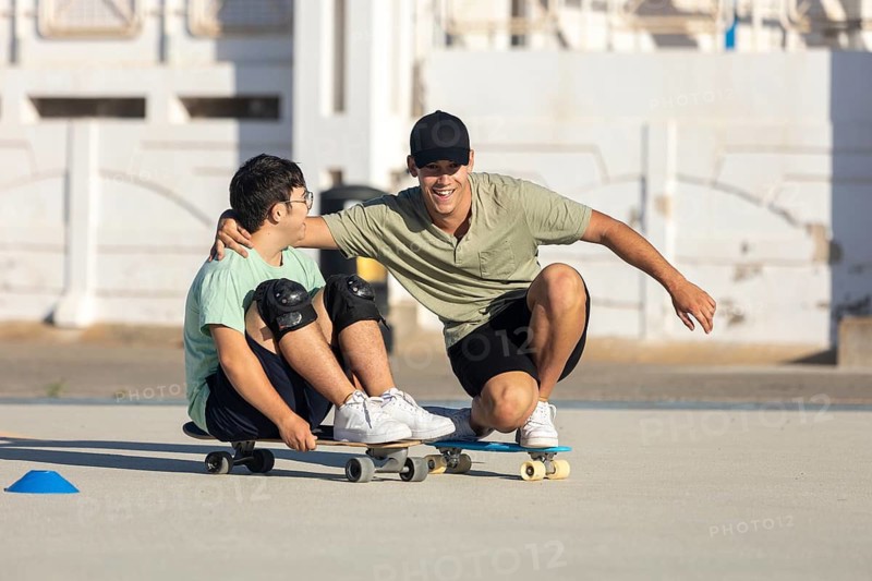 Down syndrome teenager skateboards with his brother, sharing a joyful moment and promoting inclusivity The setting emphasizes sport and connection in everyday life