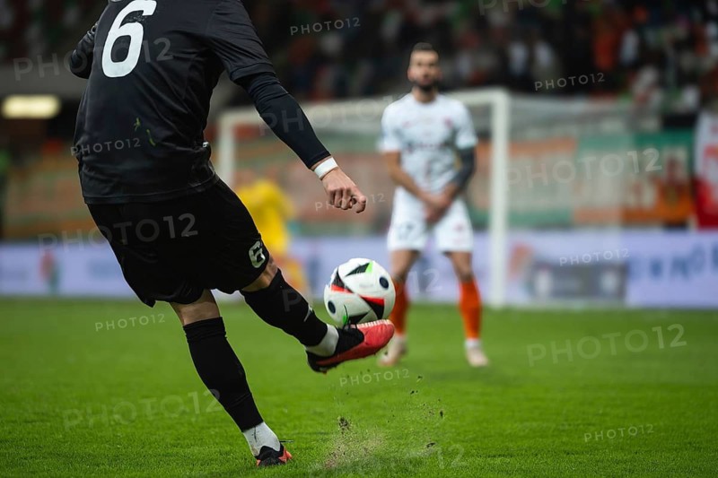 Soccer player kicks the ball during football match. Opponent player in the wall