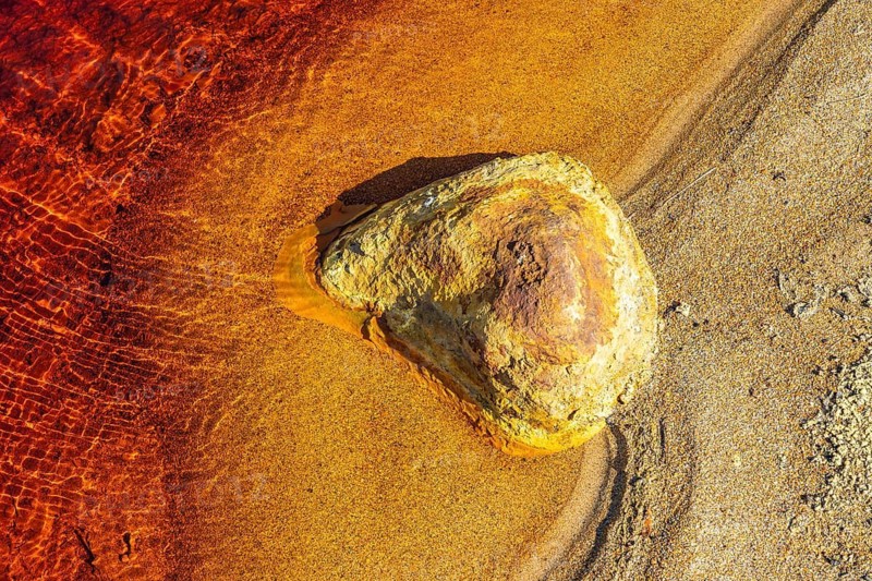 Vivid hues of red and orange characterize the Riotinto River in Huelva, Spain The rich mineral content creates a surreal, otherworldly landscape along the riverbank