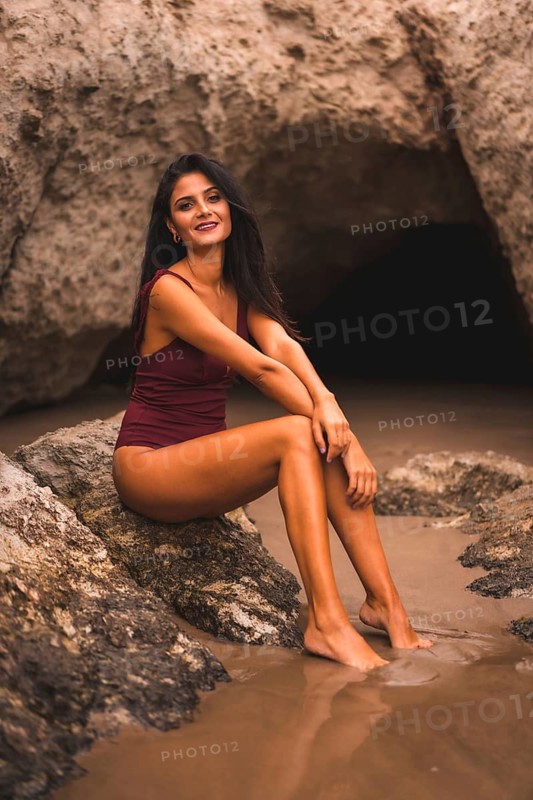 Lifestyle of a brunette Caucasian woman with a maroon swimsuit sitting, summer on the beach of Cabo de Gata, Nijar. Andalucia, Spain