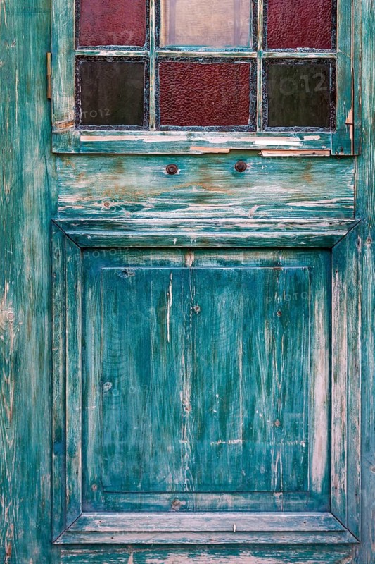 Weathered turquoise wooden door with small colourful windows, rustic and antique look, Turkey