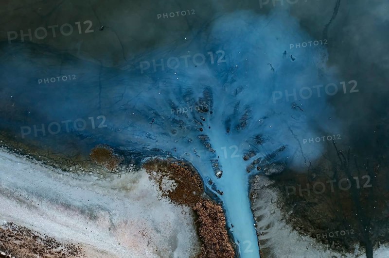 A striking aerial perspective of a lagoon in Toledo showcasing intricate natural patterns resembling branching streams. The image captures the blending of water and land in a serene, organic formation