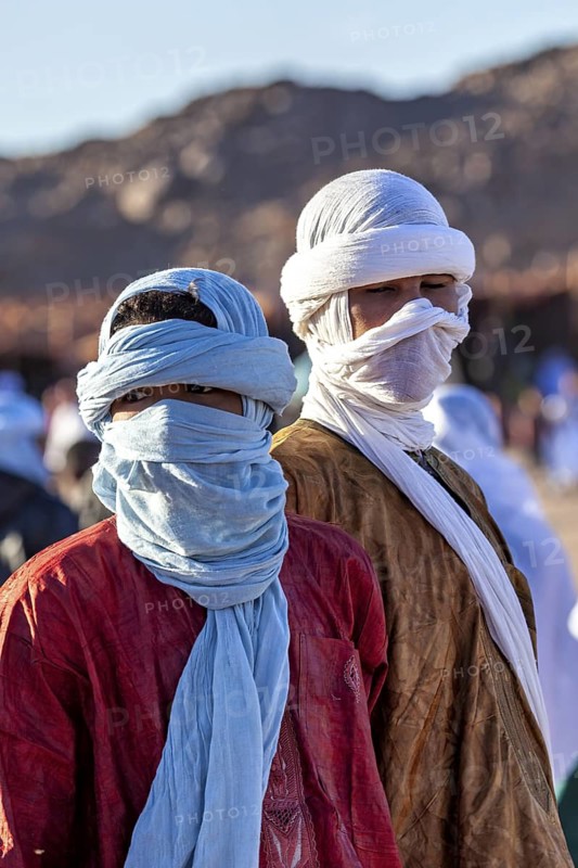Two men in colourful, traditional robes with turbans in front of a mountain, The traditional Tuareg at the Tamanrasset Festival in the Sahara in Algeria