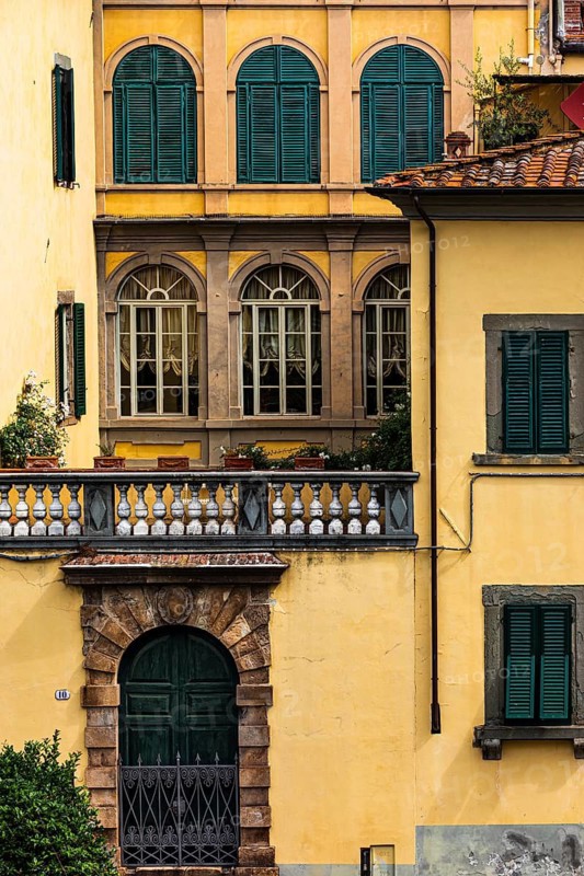 Arched entrance gate and arched windows with green shutters in a pastel-coloured façade, historic, city centre, Lucca, Tuscany, Italy