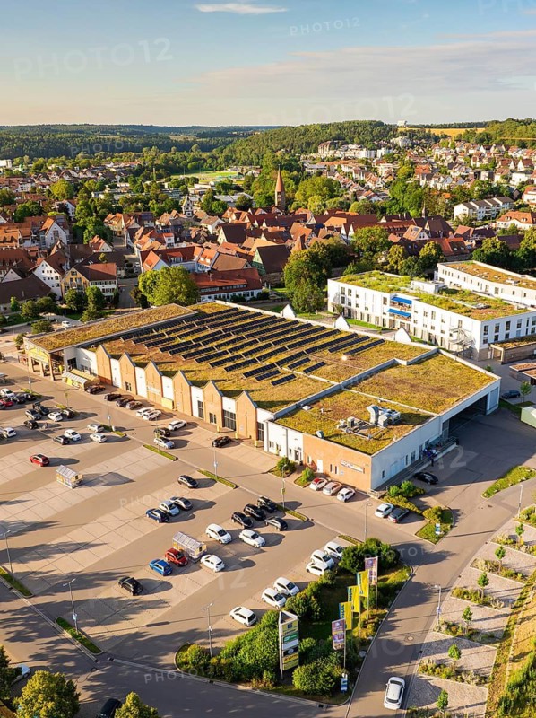 Urban aerial view of a large building with solar cells on the roof and an adjacent car park, Weil der Stadt, Germany
