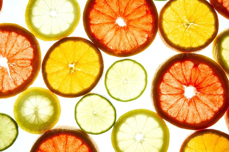 An array of colorful citrus slices, including orange, grapefruit, and lime, illuminated against a bright background. The vibrant colors and textures create an eye catching image