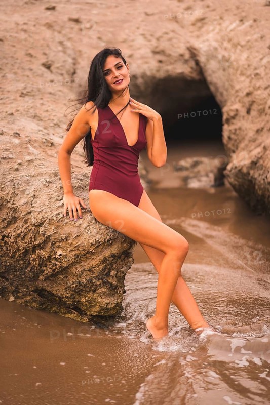 Posing of a brunette Caucasian woman with a maroon swimsuit, summer on the beach of Cabo de Gata, Nijar. Andalucia, Spain
