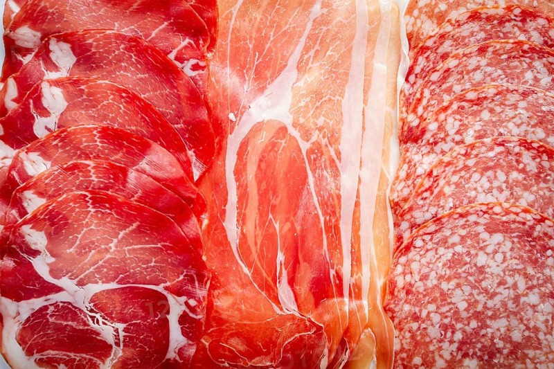 Various types of cured meats including prosciutto, salami, and other specialties are beautifully arranged on a platter, showcasing their textures and colors for a delightful culinary experience