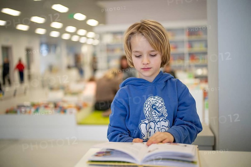 Interior shot, boy, 6 years old, blonde, reading book in the children's section of the city library, architect Eun Young Yi, Stuttgart, Baden-Württemberg, Germany