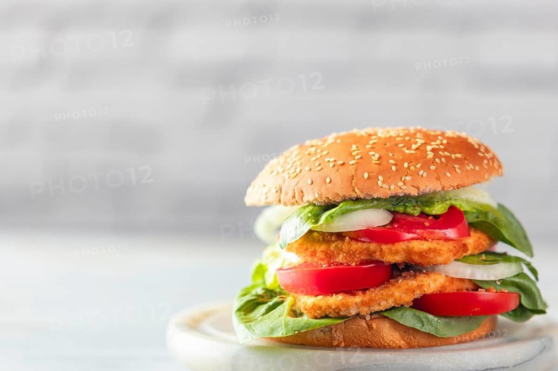 Burger with vegan schnitzel, tomatoes, onions and lettuce, bright surroundings