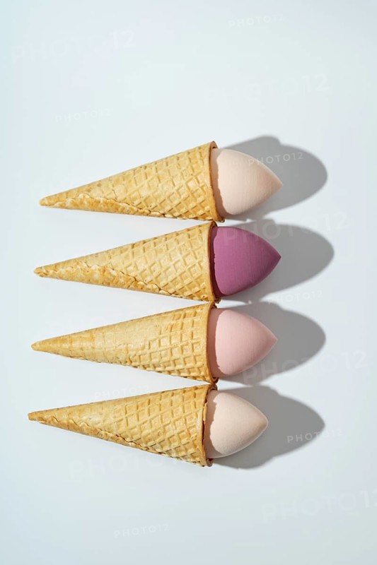 A whimsical arrangement of cosmetic sponges placed in waffle cones, resembling ice cream The pastel colors and shadows create an artistic and playful composition