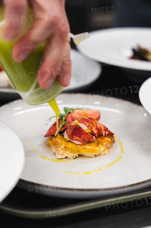 A delectable lobster dish garnished with vibrant green sauce. Fresh lobster, creamy filling, and colorful drizzle create an exquisite dining experience