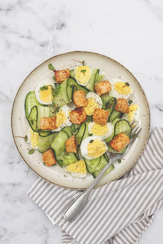 Delicious salmon and egg salad served on a plate with fresh cucumber and herbs for a healthy meal at lunchtime