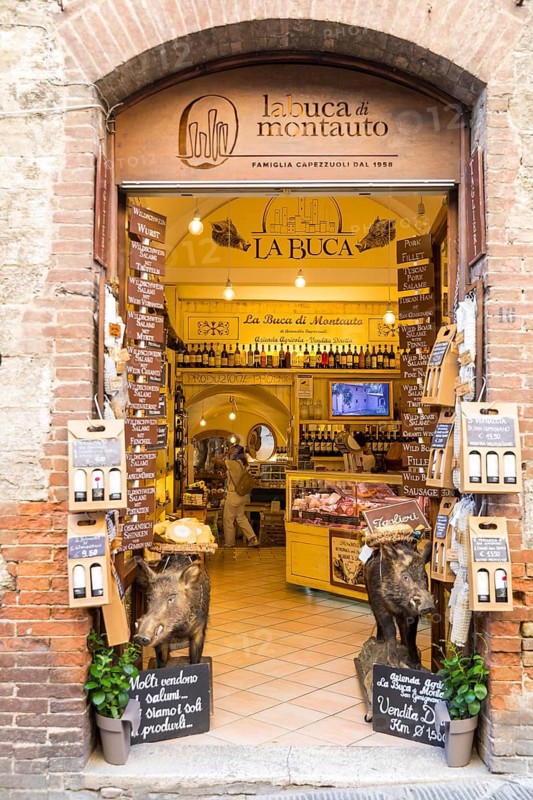 Entrance to a charcuterie shop with stuffed wild boars in front of it, historic centre of San Gimignano, province of Siena, Tuscany, Italy