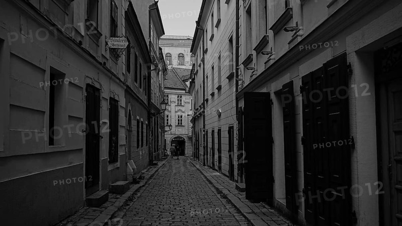 Narrow paved alley with tall, narrow older buildings, monochrome, old town of Bratislava