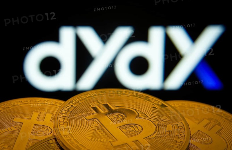 Dhaka, Bangladesh- 03 Oct 2025: Close-up of Bitcoin coins with the Dydx logo visible on a screen in the background