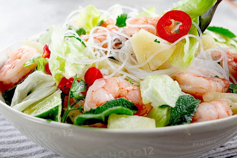 Thai salad with shrimp and rice noodles, pineapple slices, coriander and mint leaves, on a white plate, homemade, no people