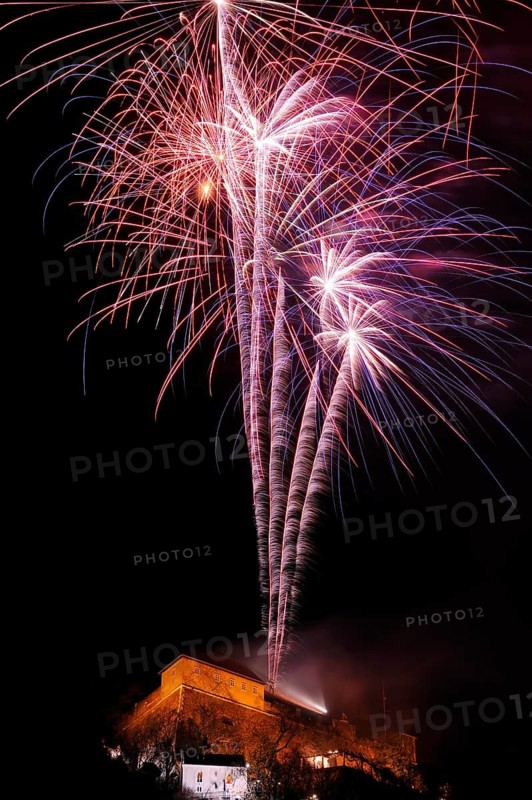 Red and blue firework rockets rise into the air and light up the dark night, New Year's Eve, Stallbastei, Schlossberg, Graz, Styria