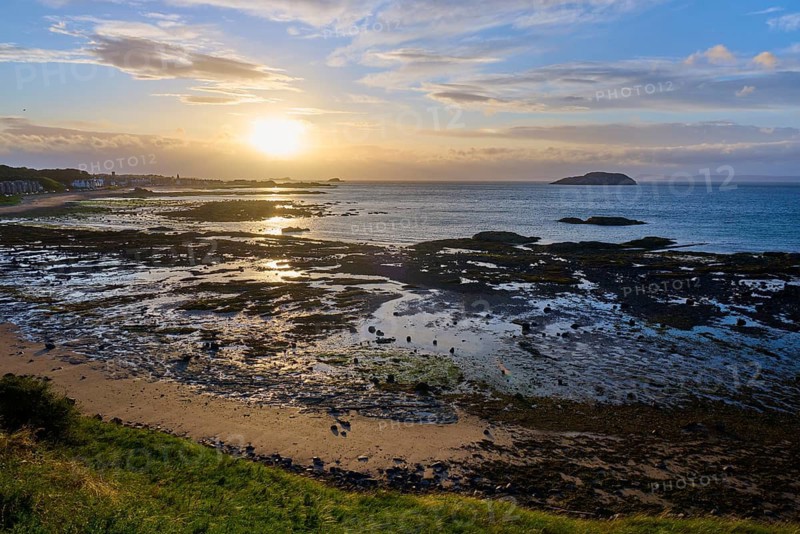 Beach landscape with sea and rocks at sunset under a cloudy sky, North Berwick, East Lothian, Scotland, United Kingdom, Great Britain