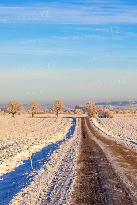 Slippery country road with snow and ice in a rural landscape by fields a cold winter day Sweden