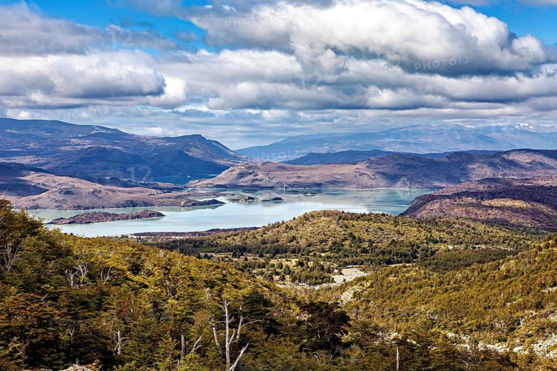 Sweeping panoramic view of a lake surrounded by mountains under a cloudy sky, The landscape of Torres del Paine National Park in Patagonia Chile