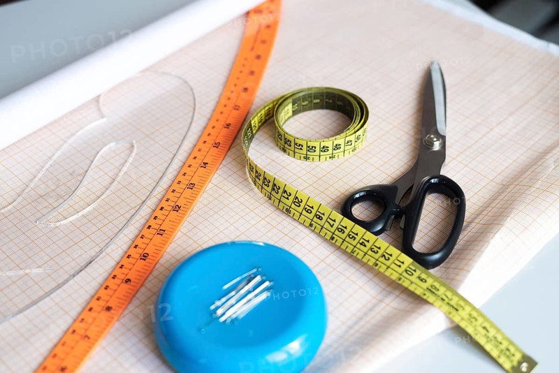 A vibrant collection of sewing essentials including scissors, measuring tape, and a ruler, all thoughtfully arranged on fabric in a workshop setting, evoking creativity and craftsmanship