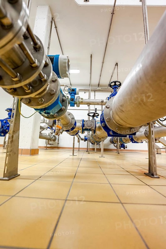 Large metal pipe with blue valve manifold on tiled floor, ENCW Netze Calw waterworks, Calw, Black Forest, Germany