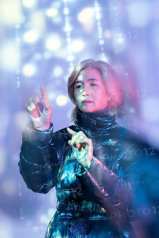 An elderly Asian woman engaging with a digital interface in the metaverse, highlighting the intersection of technology and senior citizens in a futuristic virtual environment