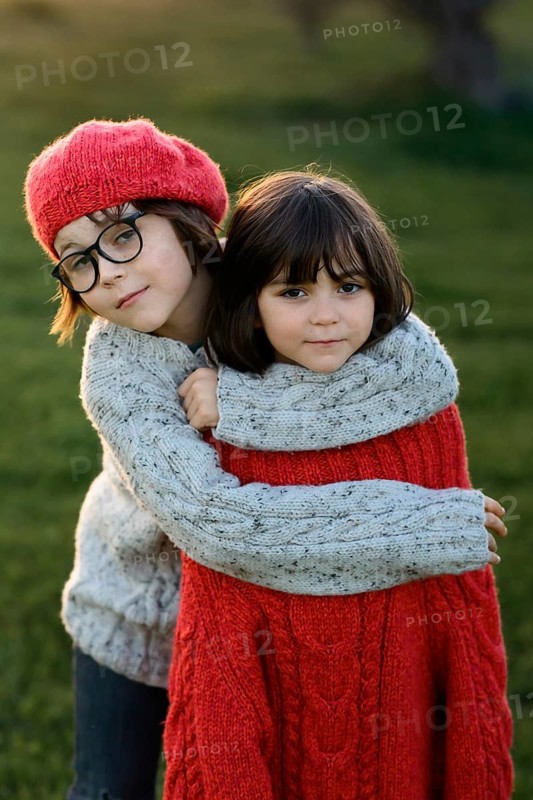 A boy and girl, siblings, warmly embrace in an autumn park setting, showcasing expressions of comfort and closeness