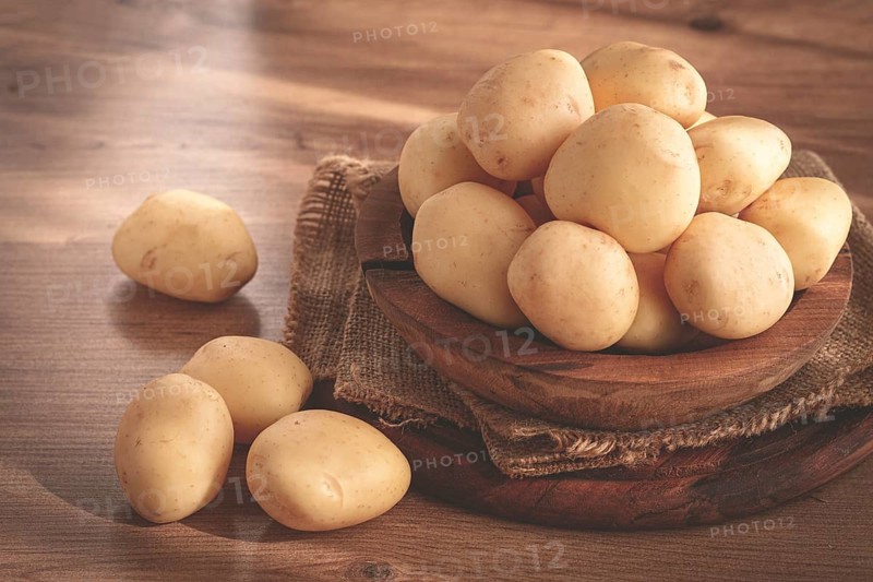 Boiled new potatoes, in a wooden bowl, on a rustic table, natural light, no people