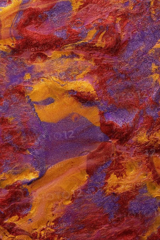 Close-up view of a vibrant, abstract metallic paint blend of red, purple, and gold hues. Ideal for use in artistic backgrounds and designs