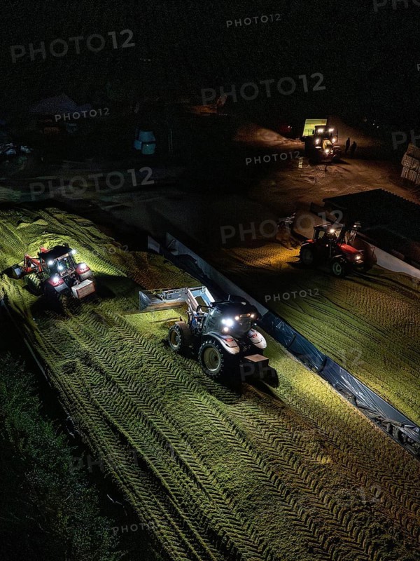 Several tractors working at night with headlights on a rural field, maize harvest, Dachtel, Black Forest, Germany