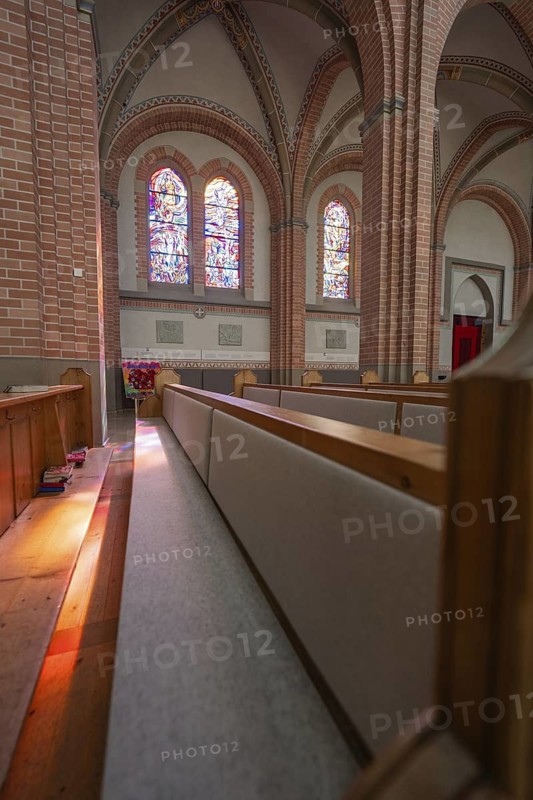 Close-up of church pews with light reflections from colorful windows, Sacred Heart, Bregenz, Austria