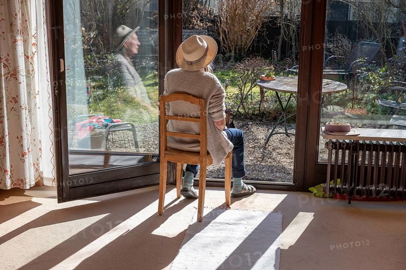 Woman wearing hat sunbathing with patio door open, Bavaria, Germany