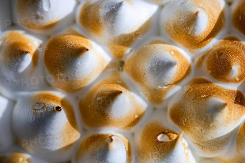 A close up image showcasing the beautifully browned peaks of a homemade lemon cake. The texture and color contrast highlight the art of culinary presentation and dessert decoration