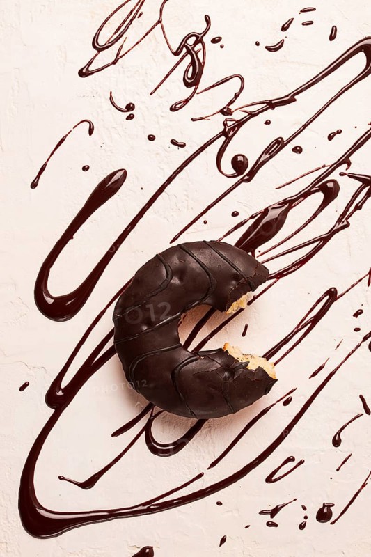 Donuts, in chocolate glaze, on a beige background, with liquid chocolate