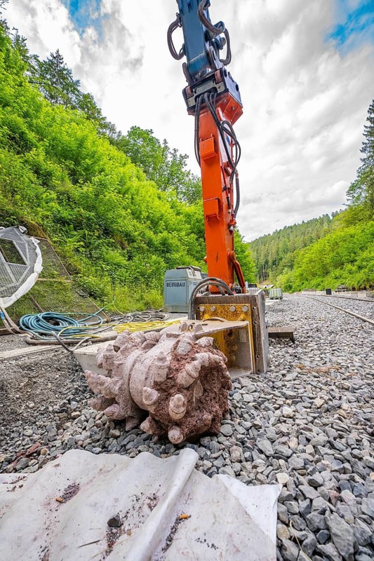 Large machine and tools on a railway construction site in a green, wooded environment, track construction Hermann Hesse Bahn, Calw, Black Forest, Germany
