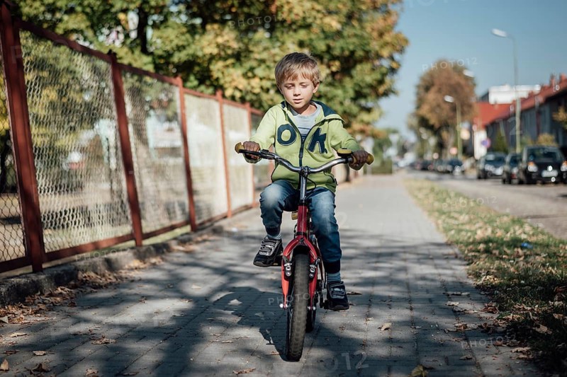 Little boy on a bicycle ride on a pavement in a town