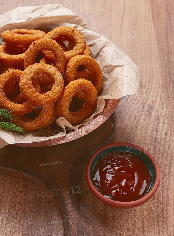 Deep fried onion rings, appetizer, with tomato sauce, on a wooden table, no people, favorite dish
