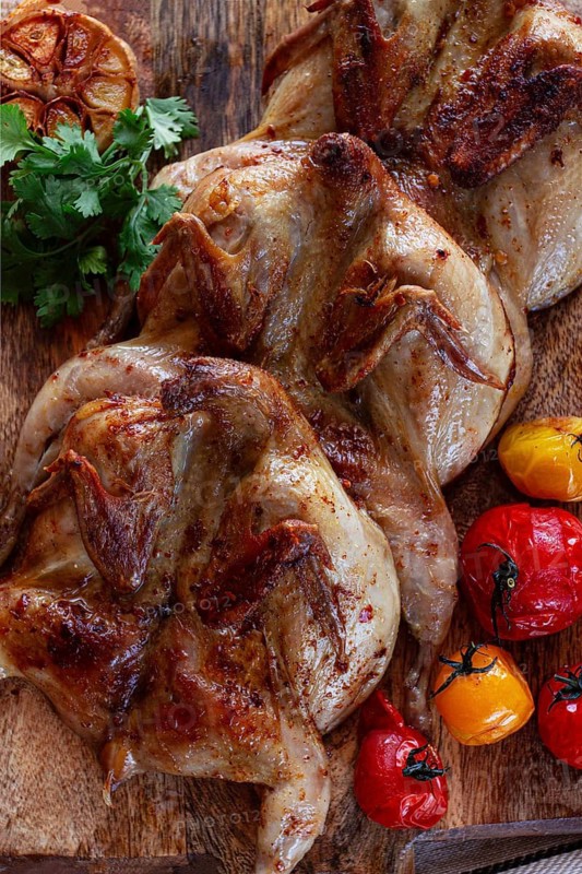 Grilled quail meat, on a wooden chopping board, tobacco, in the oven, with spices, homemade, without people