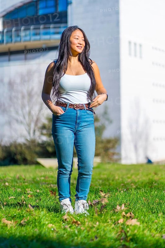 Vertical photo of a chinese cool student standing on the grass of the campus