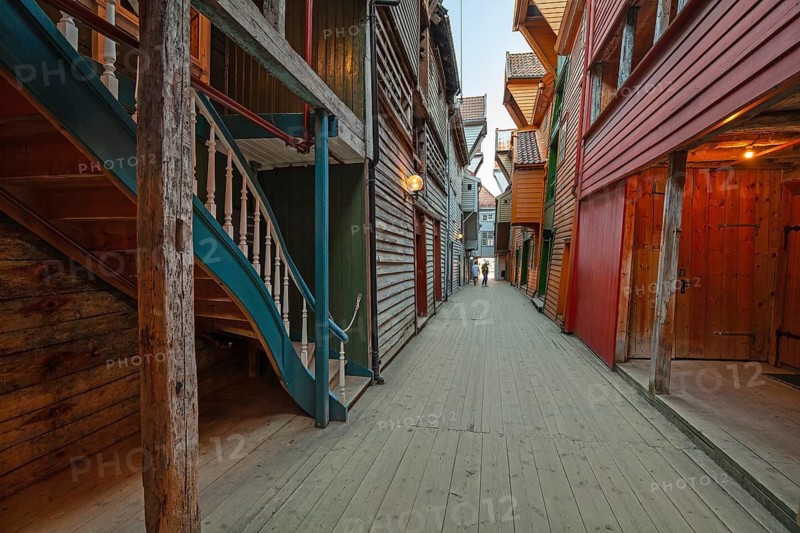 Summer day exploring behind facades in Bryggen Bergen, narrow lanes, colorful wooden buildings, historic trade stores, Vestland, Norway