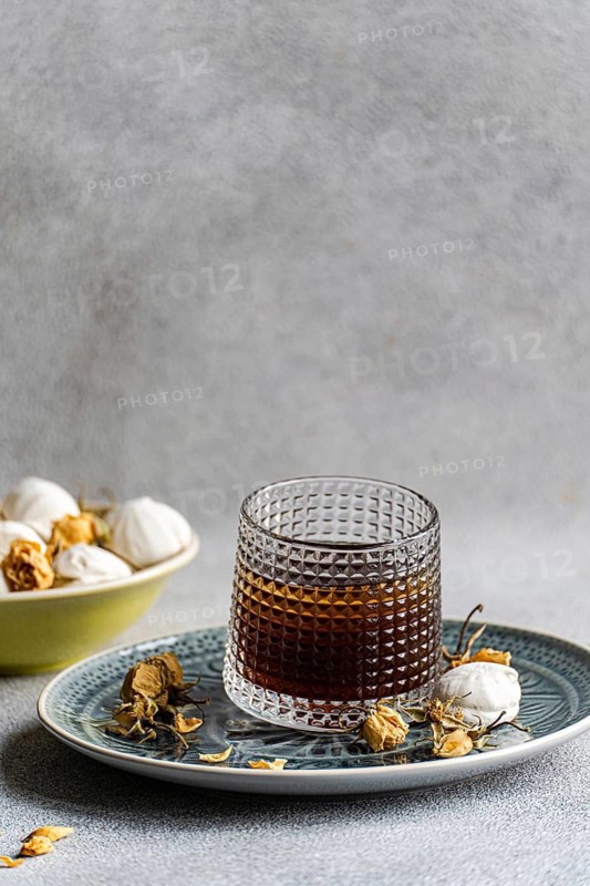A delectable homemade vanilla mini zephyr-marshmallow filled with rose jam, paired with a refreshing coffee liqueur drink served over ice for a delightful treat
