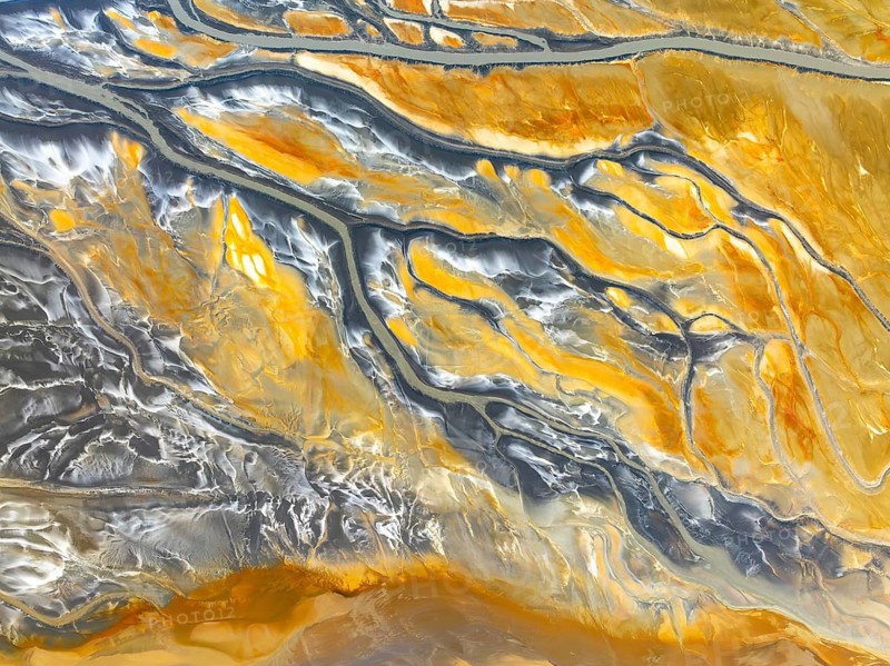 From above, an aerial drone captures the intricate patterns of abstract nature textures, showcasing a mesmerizing blend of yellow and grey hues that create dynamic lines and forms on Earth's surface