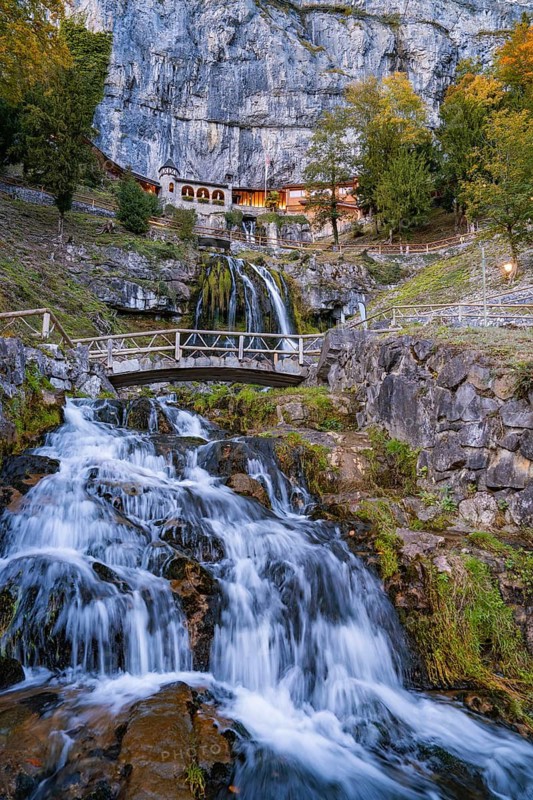 A waterfall flowing over rocks with a bridge in the foreground, St. Beatus Hö Lake Brienz, Switzerland