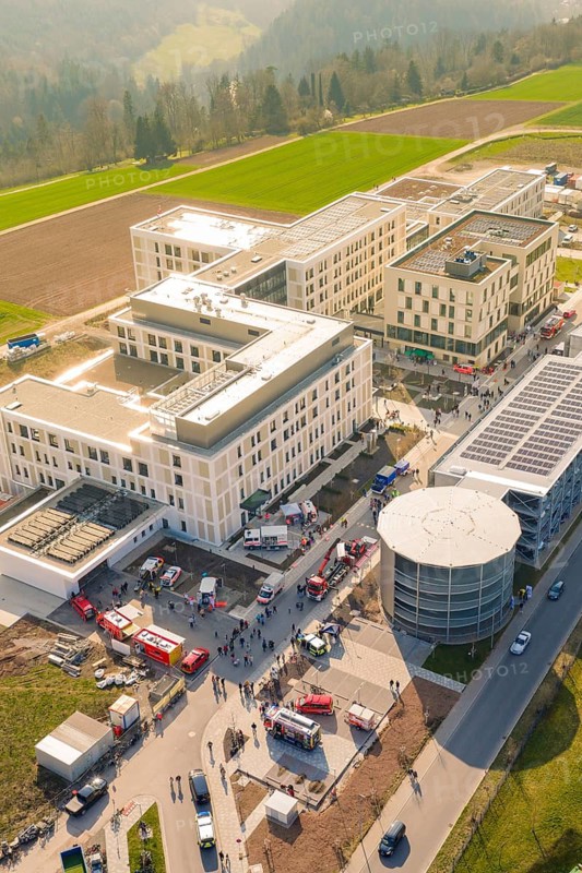 Aerial view of a large building complex with surrounding fields and vehicles, hospital opening, Calw, Germany