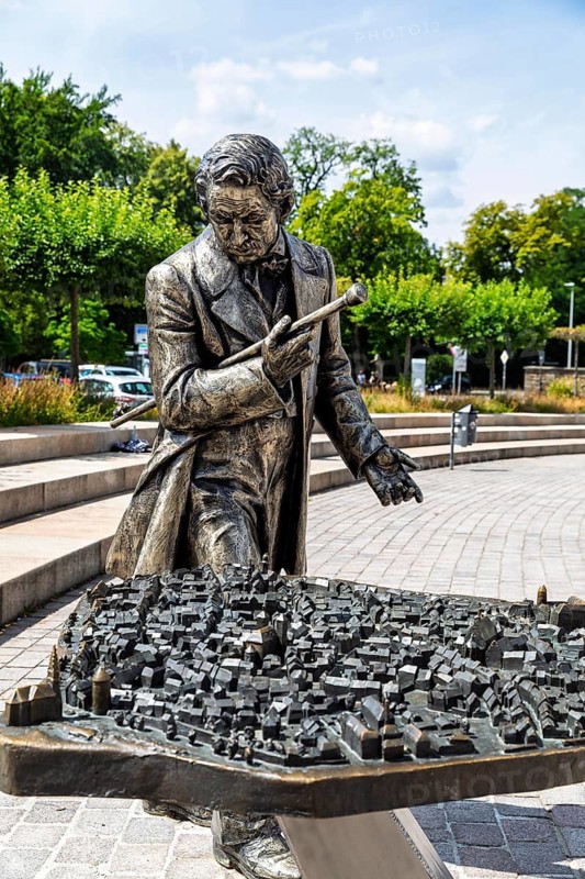 Silver figure explorer traveling by Ekaterina Kovalenko on Castle Square with bronze model of the old town, stop on the Siberweg adventure trail through the old town of Freiberg, Saxony, Germany
